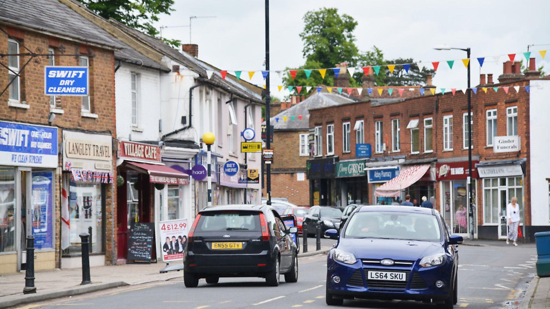 The parade of shops along Abbots Langley High Street, bunting strung across the road and traffic moving through past the kerb