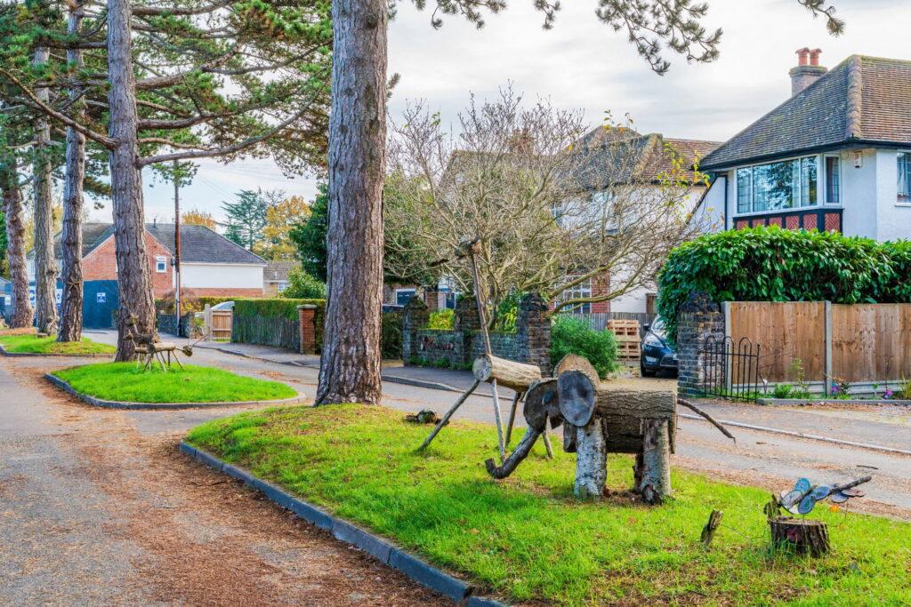A quiet residential road in Croxley Green with tall pines on a wide grass verge and interwar houses set back behind hedges